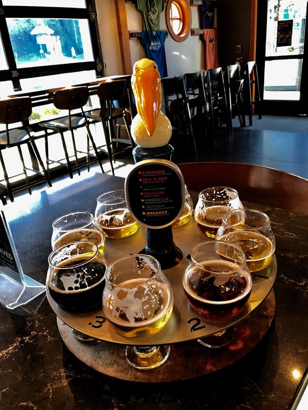 A decorative pelican tops a flight tray from Pelican brewery. Pelican brewing is one of the best breweries Oregon Coast.