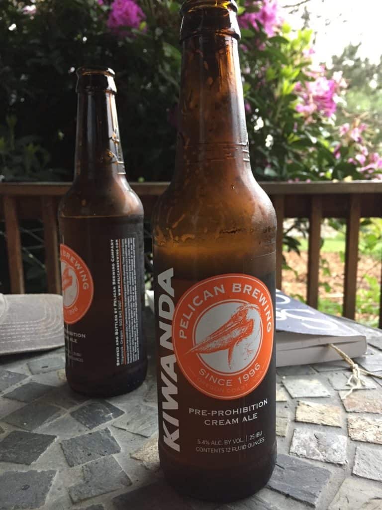 Two bottles of Kiwanda Cream Ale sit on a garden table. Pelican Brewing is one of the top breweries Oregon Coast.