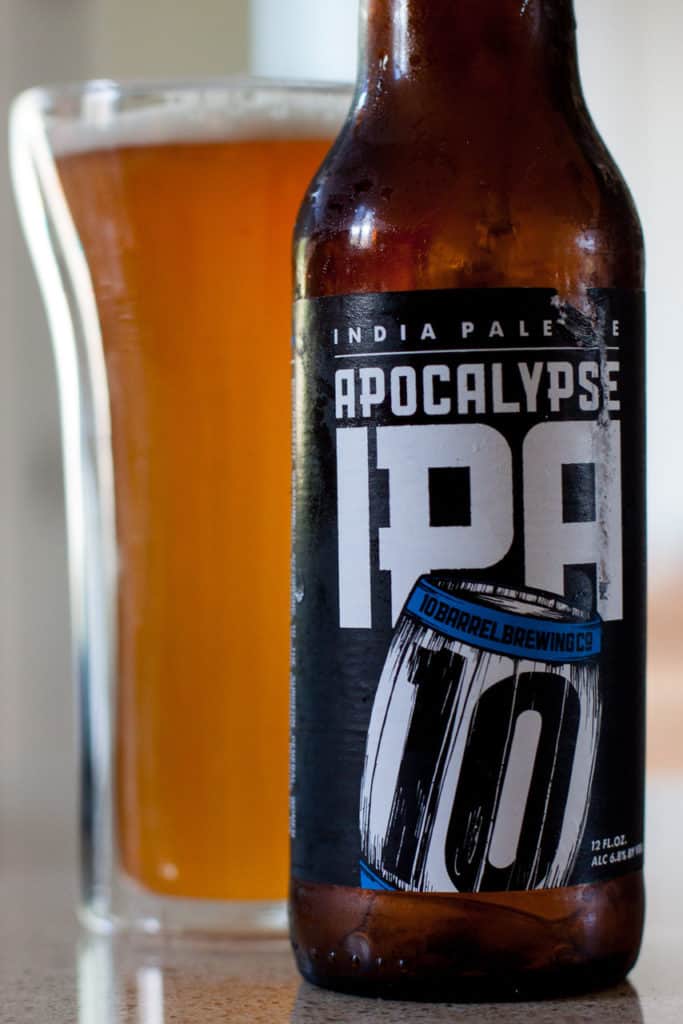 Image shows a glass full of 10 Barrel's Apocalypse IPA beside its respective bottle.