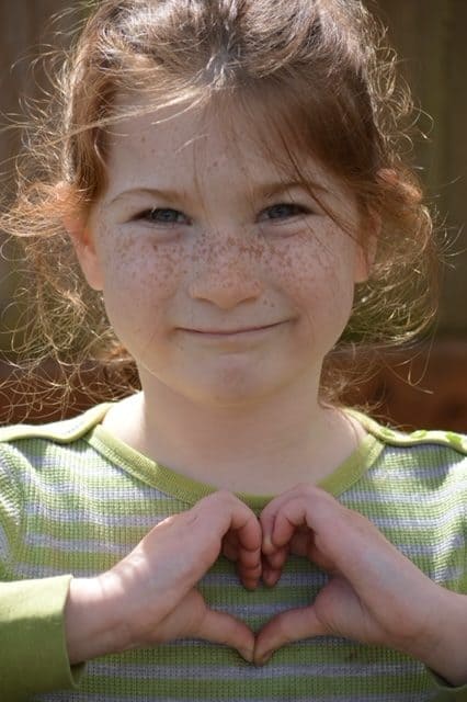 Girl making a heart shape with her hands.