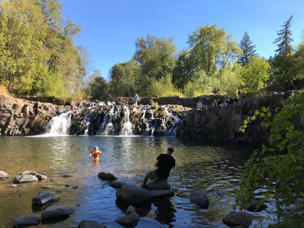 Families play along Scott's Mills Falls near Silver Falls State Park. Visiting nearby waterfalls is one of many things to do at Silver Falls State Park.