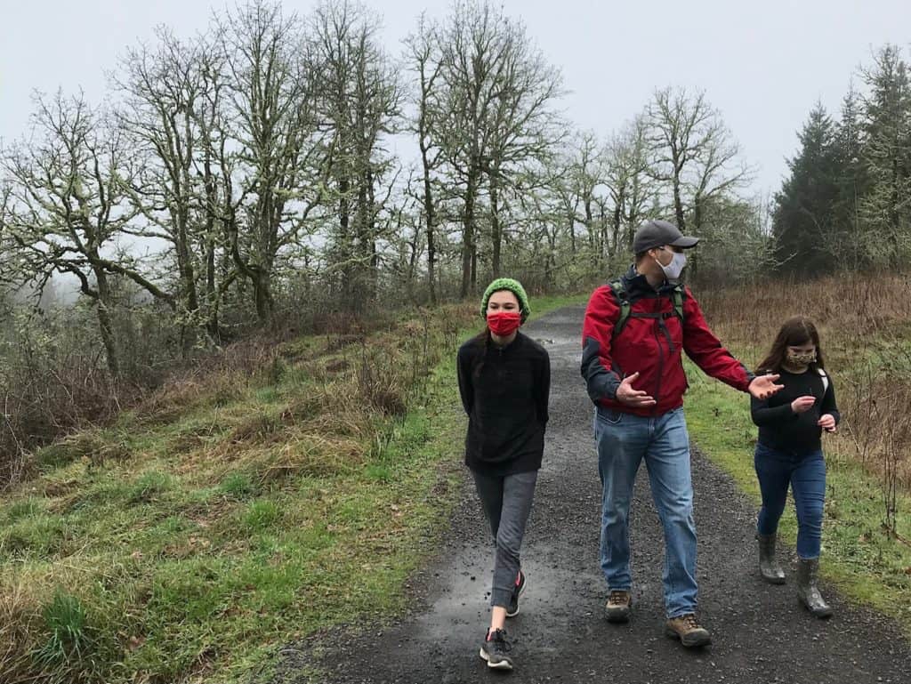 Man and two girls walking along muddy pathway.