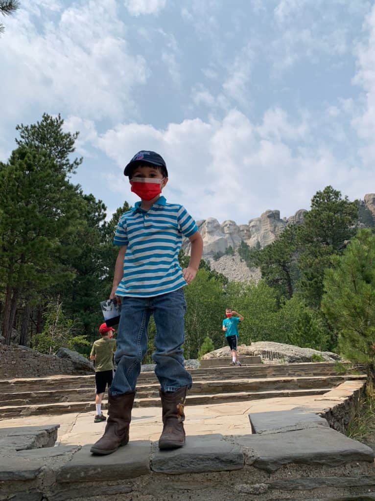A young boy stands tall with Mount Rushmore in the background.