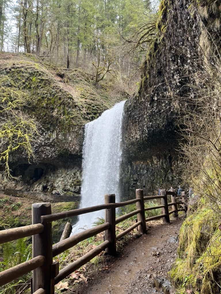 The wet, graveled Trail of Ten Falls works its way behind Lower South Falls at Silver Falls State Park.