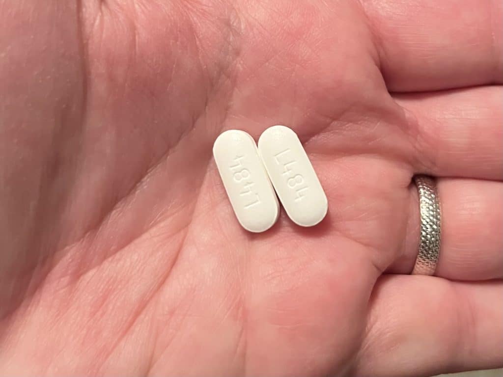 Two acetaminophen tablets on the palm of a hand. 