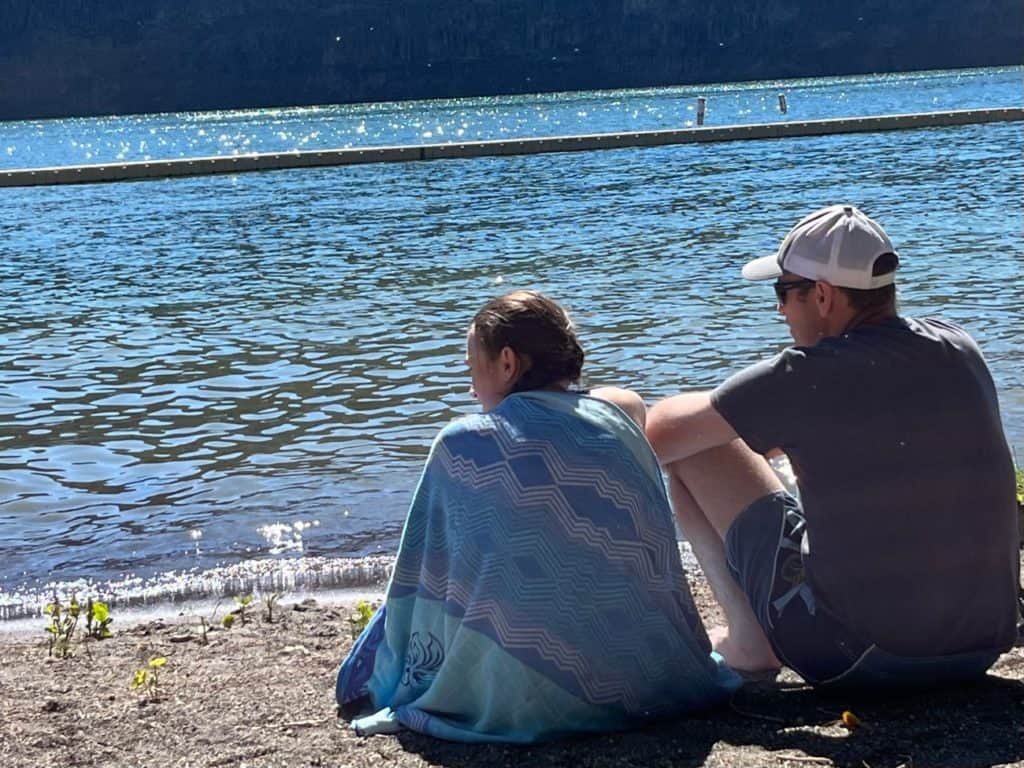 Girl and dad sitting by lake. Protecting kids from toxic family.