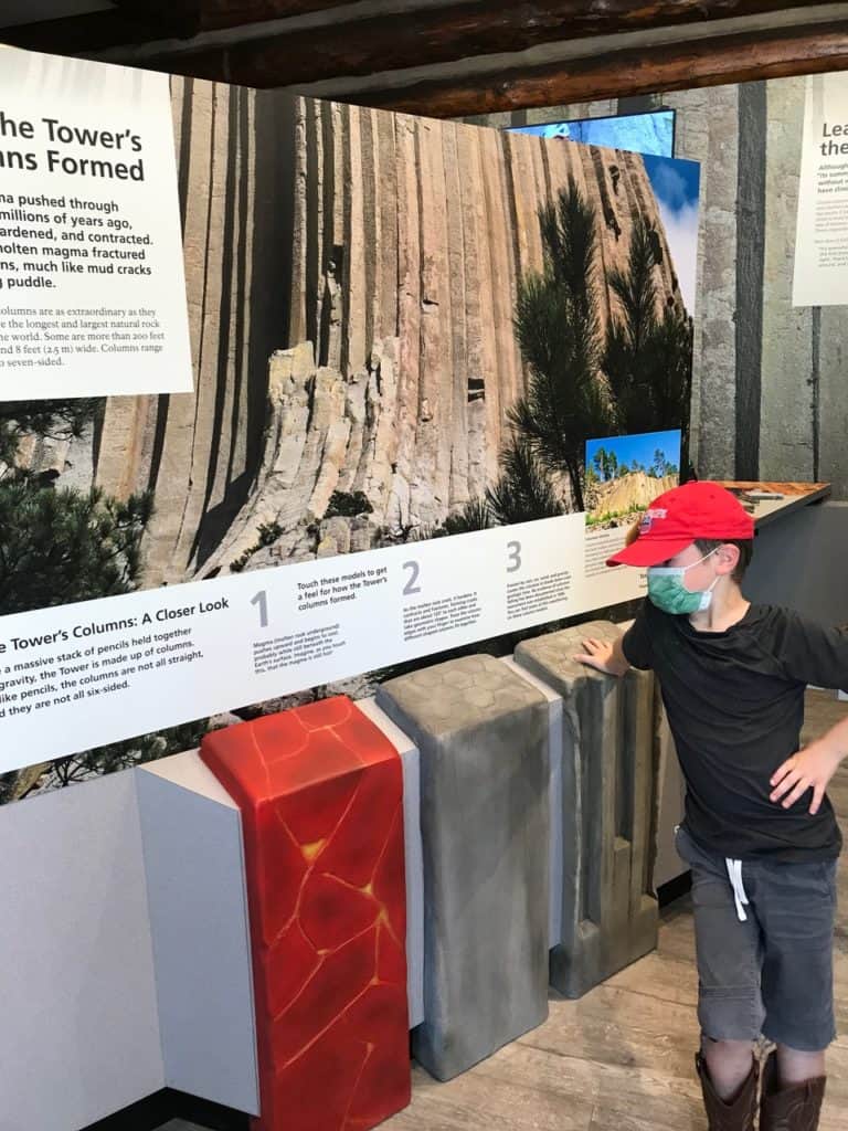 I boy studies a large, colorful display that explains the formation of the columns that make up Devil's Tower.
