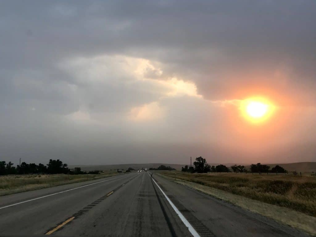 The sun penetrates through the gloom over a Eastern Montana highway.