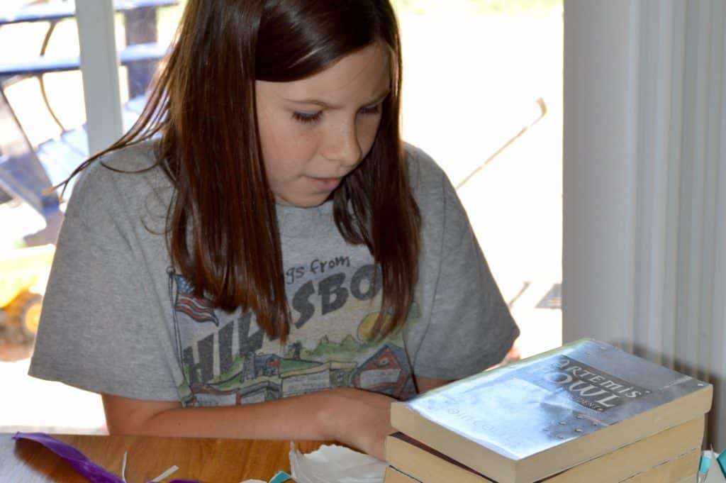 Girl looking at Artemis Fowl books. science fiction books for 5th graders