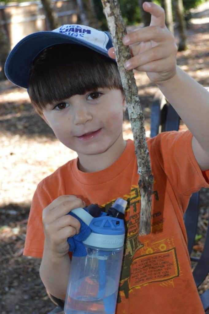 Boy holding stick and water bottle. camping gifts for kids