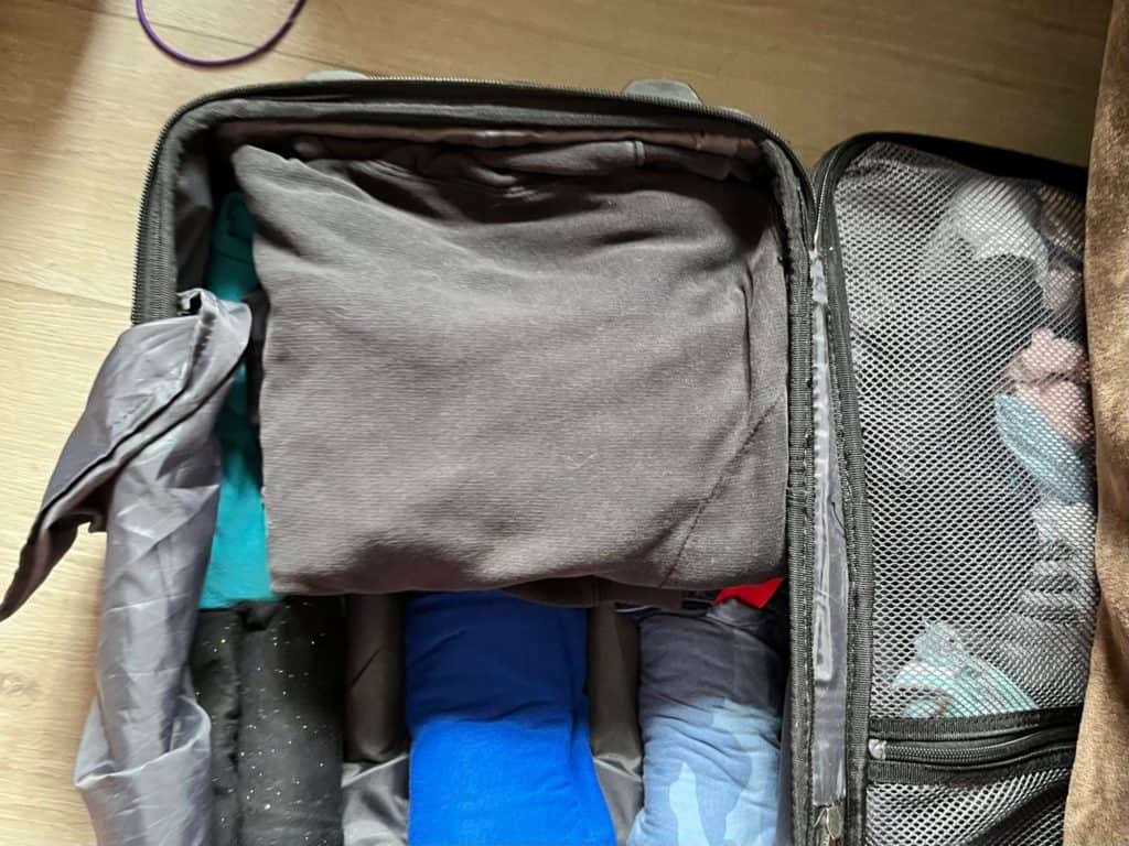 Suitcase partially packed with rolled up clothes. camping gifts for kids