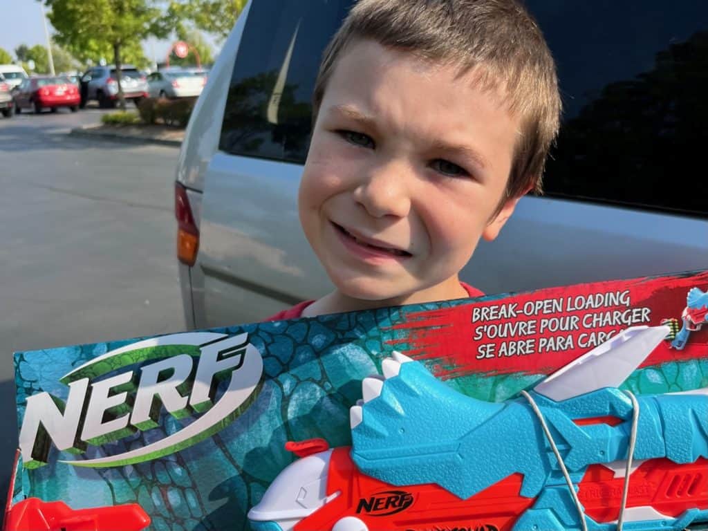 Boy holding triceratops nerf gun.