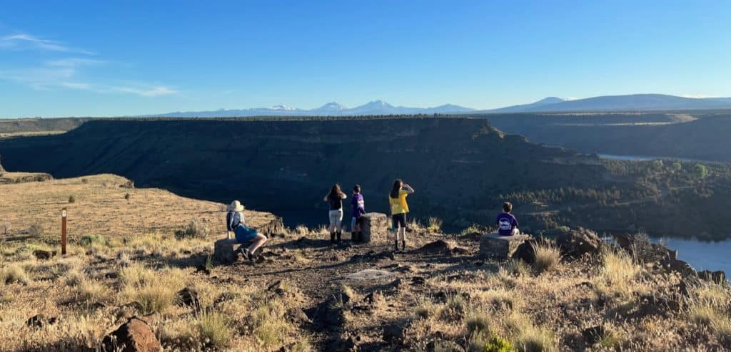 Five children look over the canyon and mountain scenery from a viewpoint at Cove Palisades State Park.