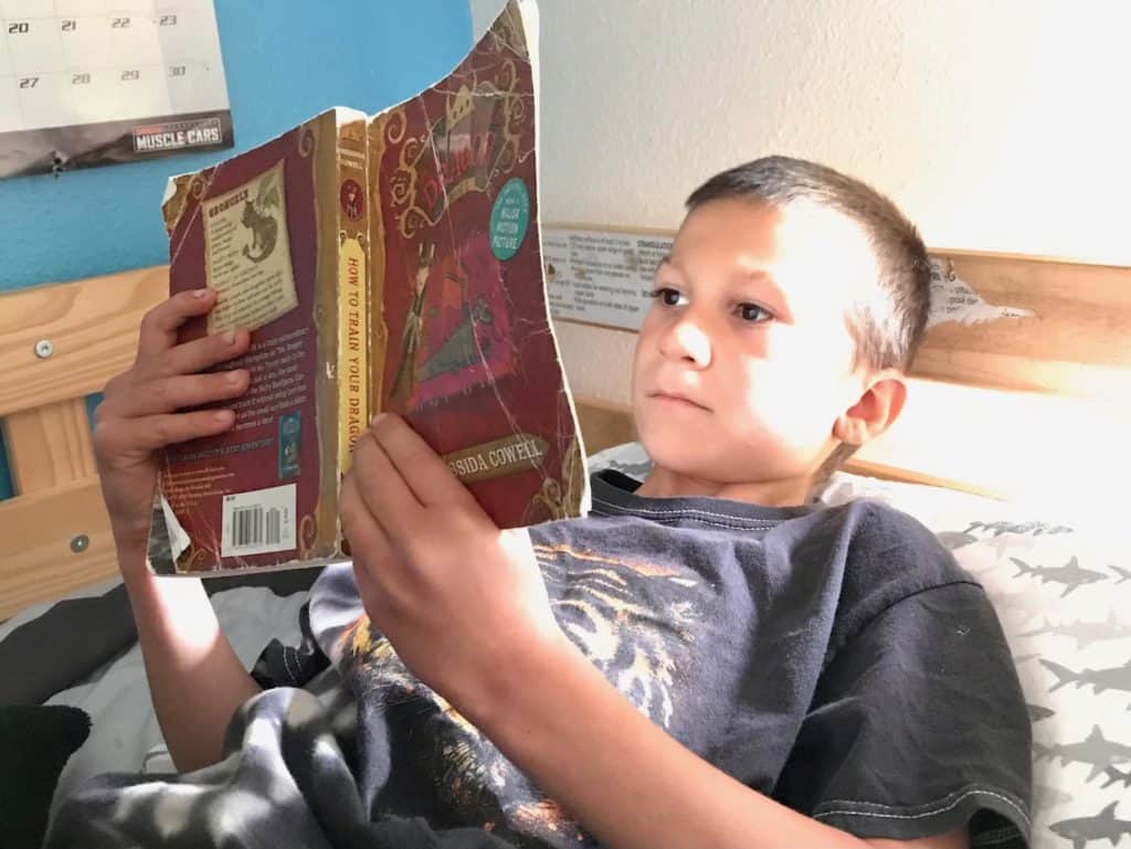 Boy reading in bed. Science fiction books for 5th graders