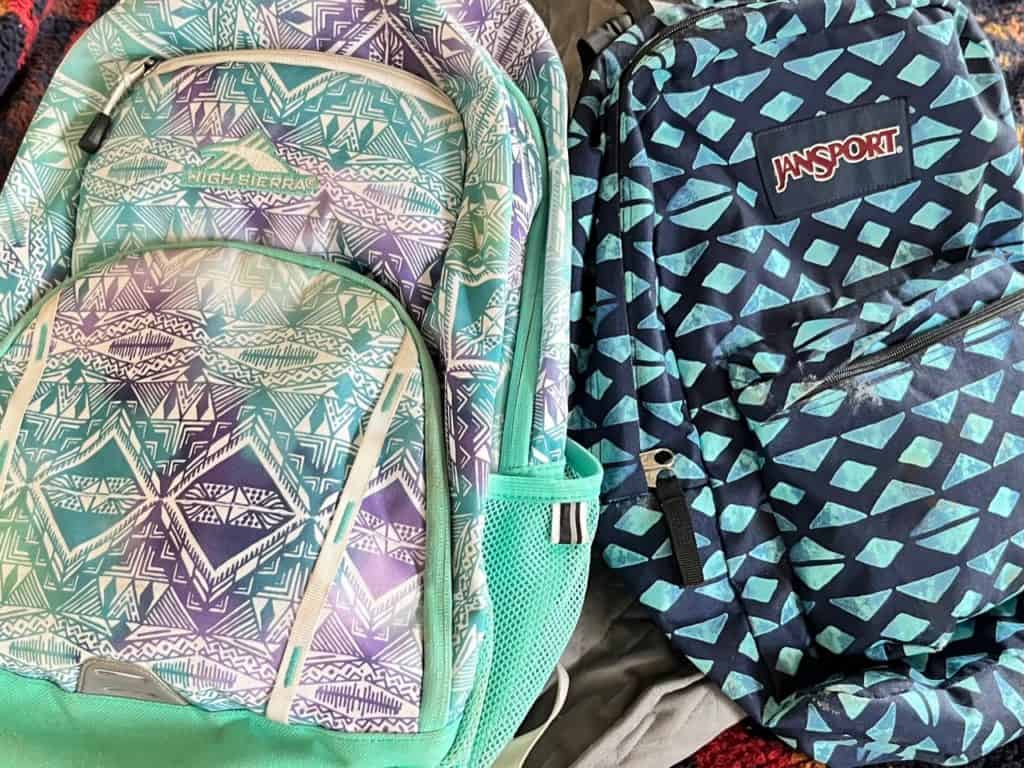 JanSport and High Sierra backpacks on our bed. Camping gifts for kids