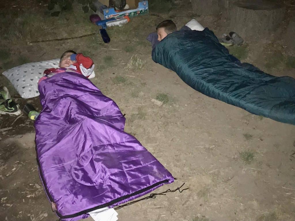 Boys in sleeping bags outside on dirt. camping gifts for kids
