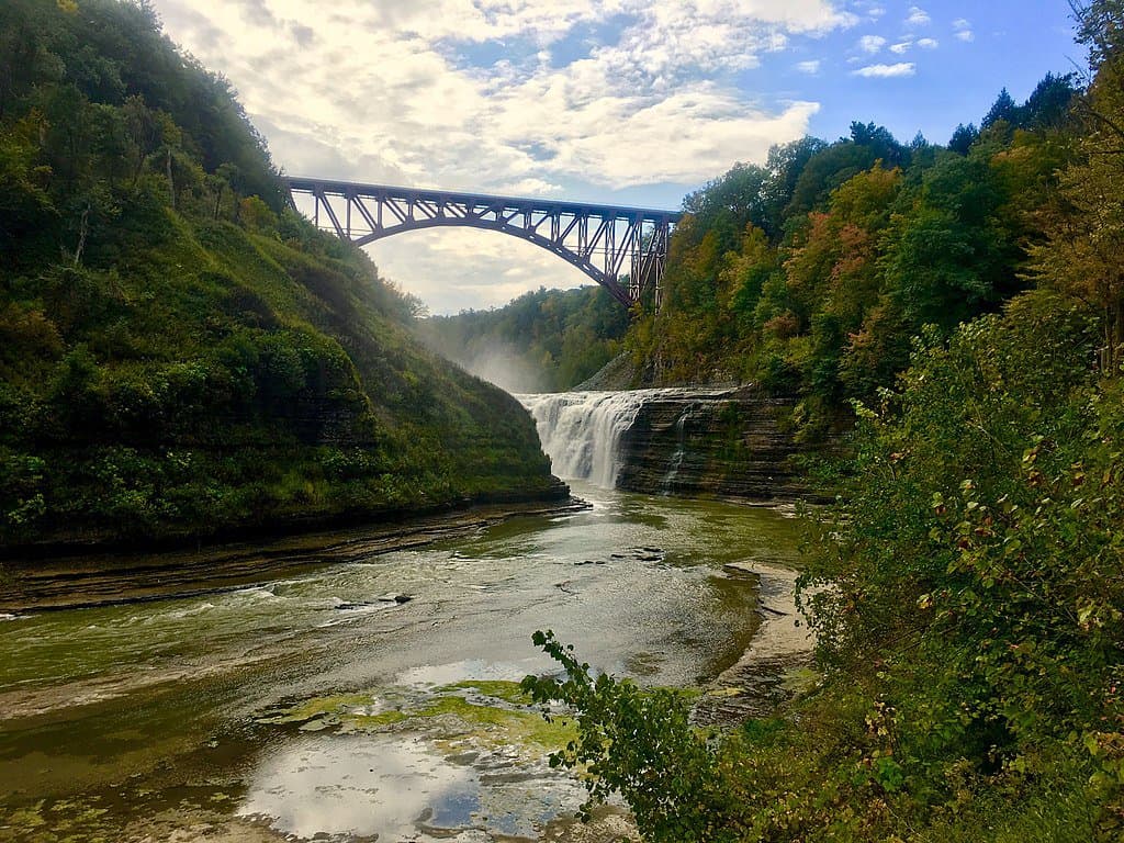 Water cascades from a waterfall below the Genesee Arch Bridge. The Genesee Arch Bridge is one of the highest bridges in the US.