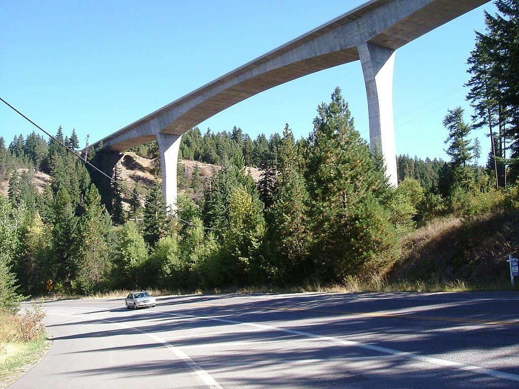 The Veterans Memorial Centennial Bridge towers over a car driving along a nearby street.