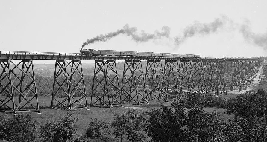A steam locomotive crosses the incredible Kate Shelley Bridge in a historic, black and white photo.