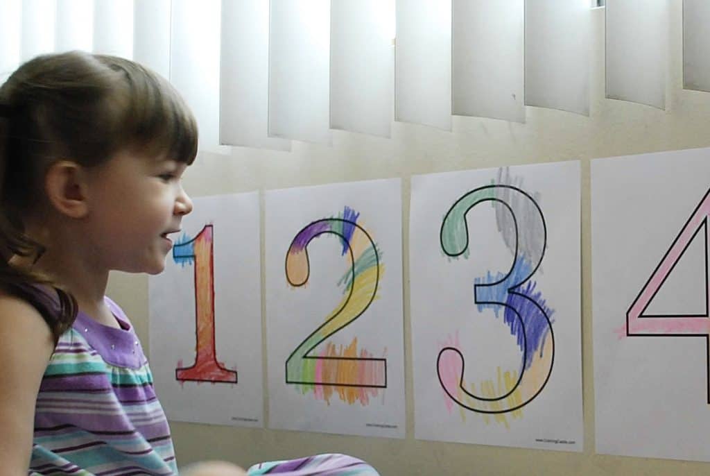 Girl with colored numbers on wall in front of her. How to start homeschooling today.