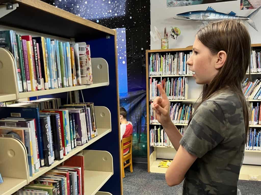 Girl choosing books at the library. How to start homeschooling today.