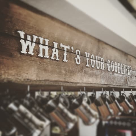 Mugs hang under a beam that says "What's your GoodLife?" at GoodLife Brewing in Bend, Oregon. Bend is close to the breweries in Redmond Oregon.
