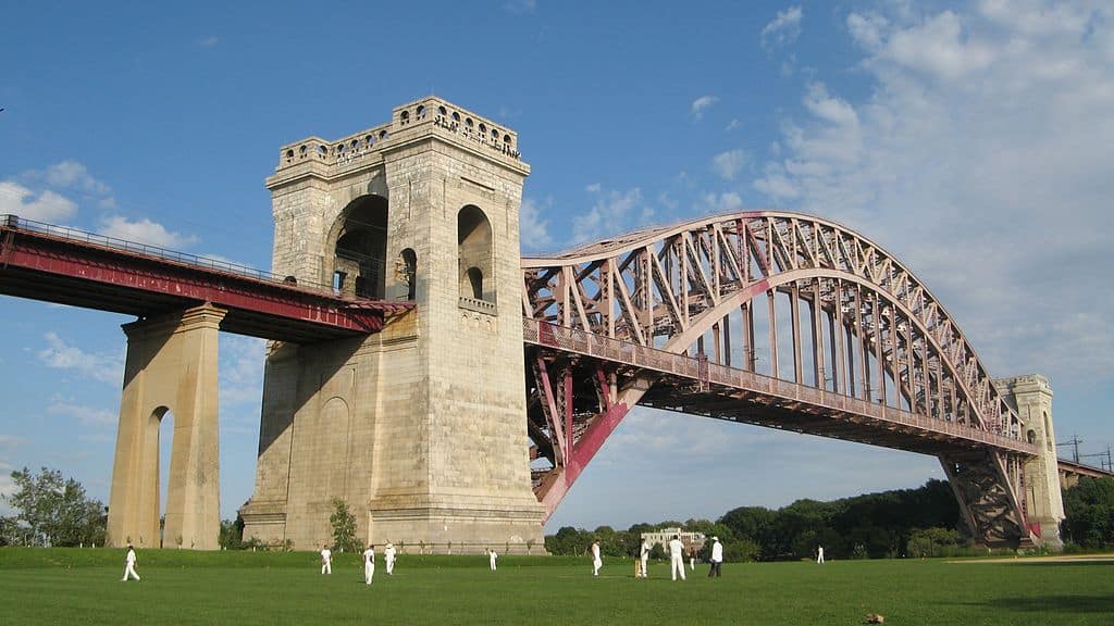 People play at a park beside the Hell Gate Bridge.