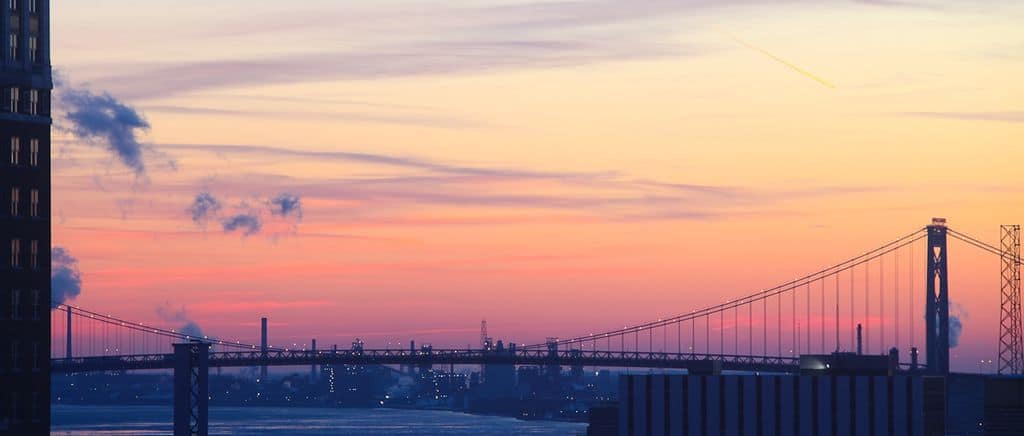 The Ambassador Bridge stands silhouetted against the Detroit sunset.