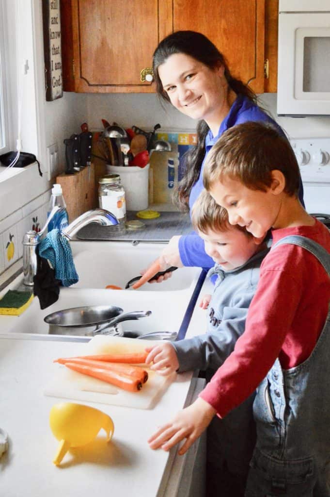 Mom and boys prepping food at the kitchen sink.