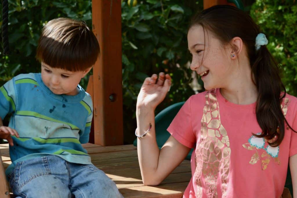 Girl laughing with toddler boy. good sibling relationships.