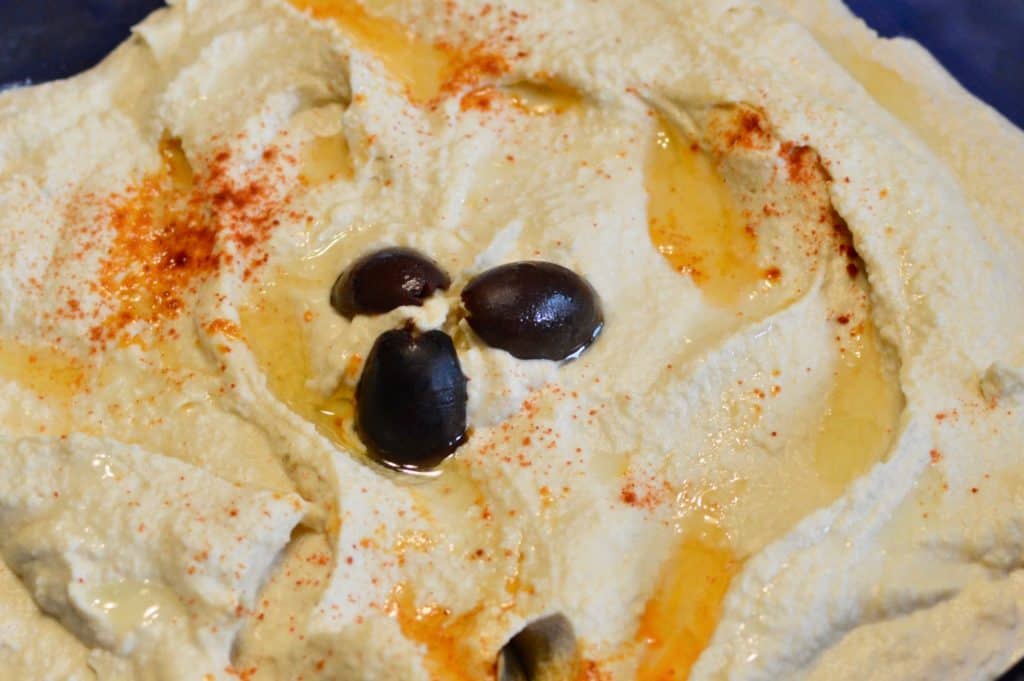 Hummus topped with paprika and olives. Camping lunch ideas.