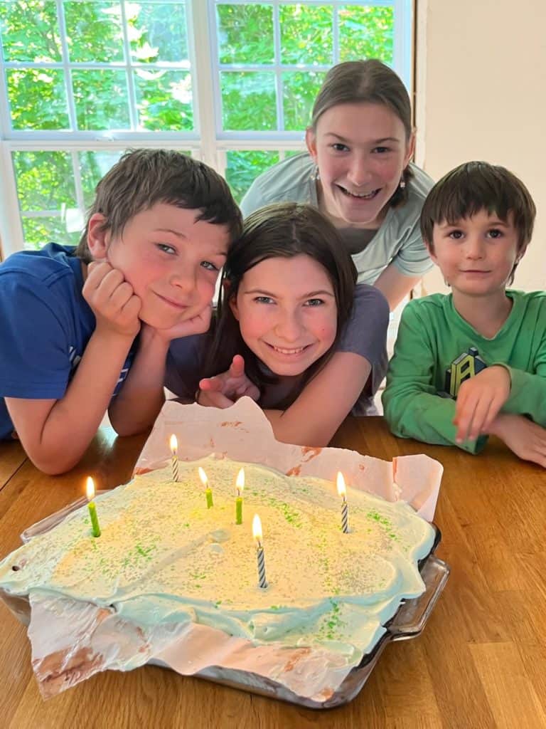 kids smiling with a birthday cake.