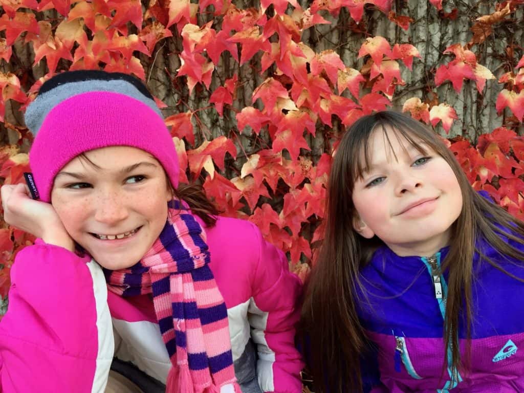 Girls in front of red fall leaves. 