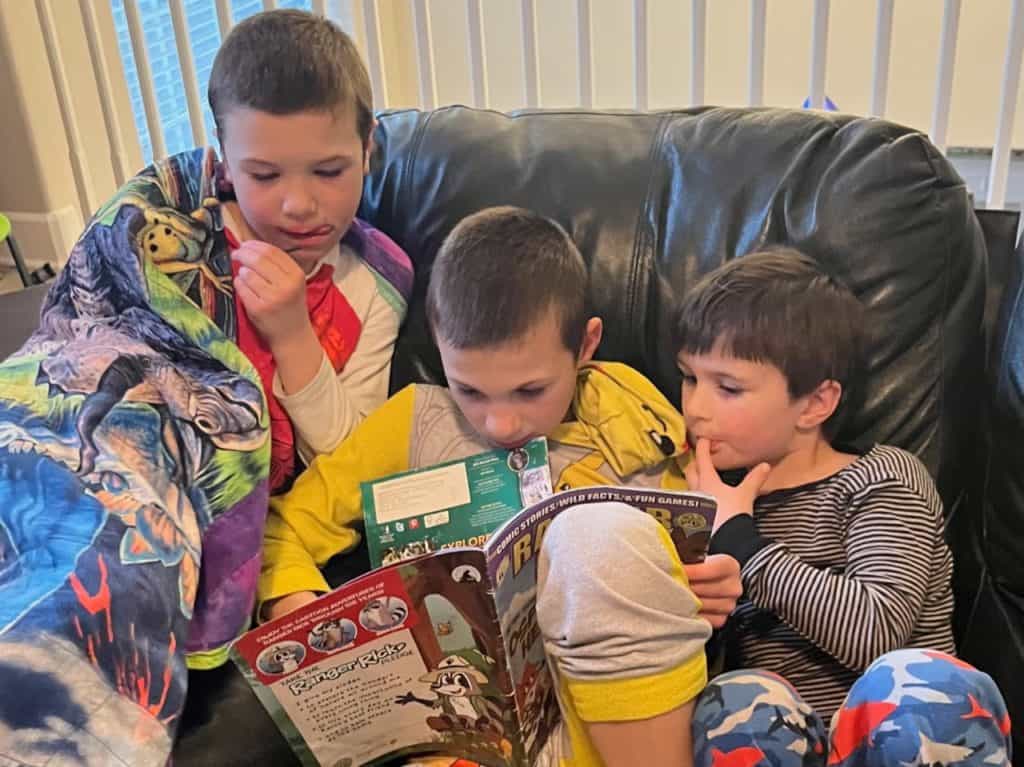 Boys reading magazines on a couch.