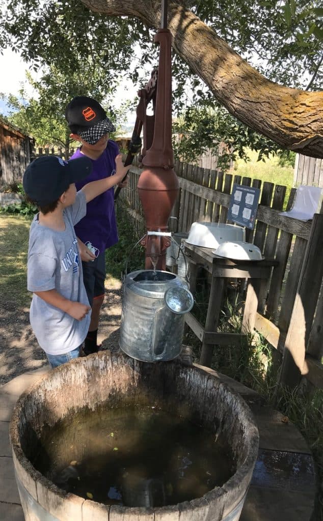 Our two boys pump water with a pioneer well pump at the Living History Exhibit.
