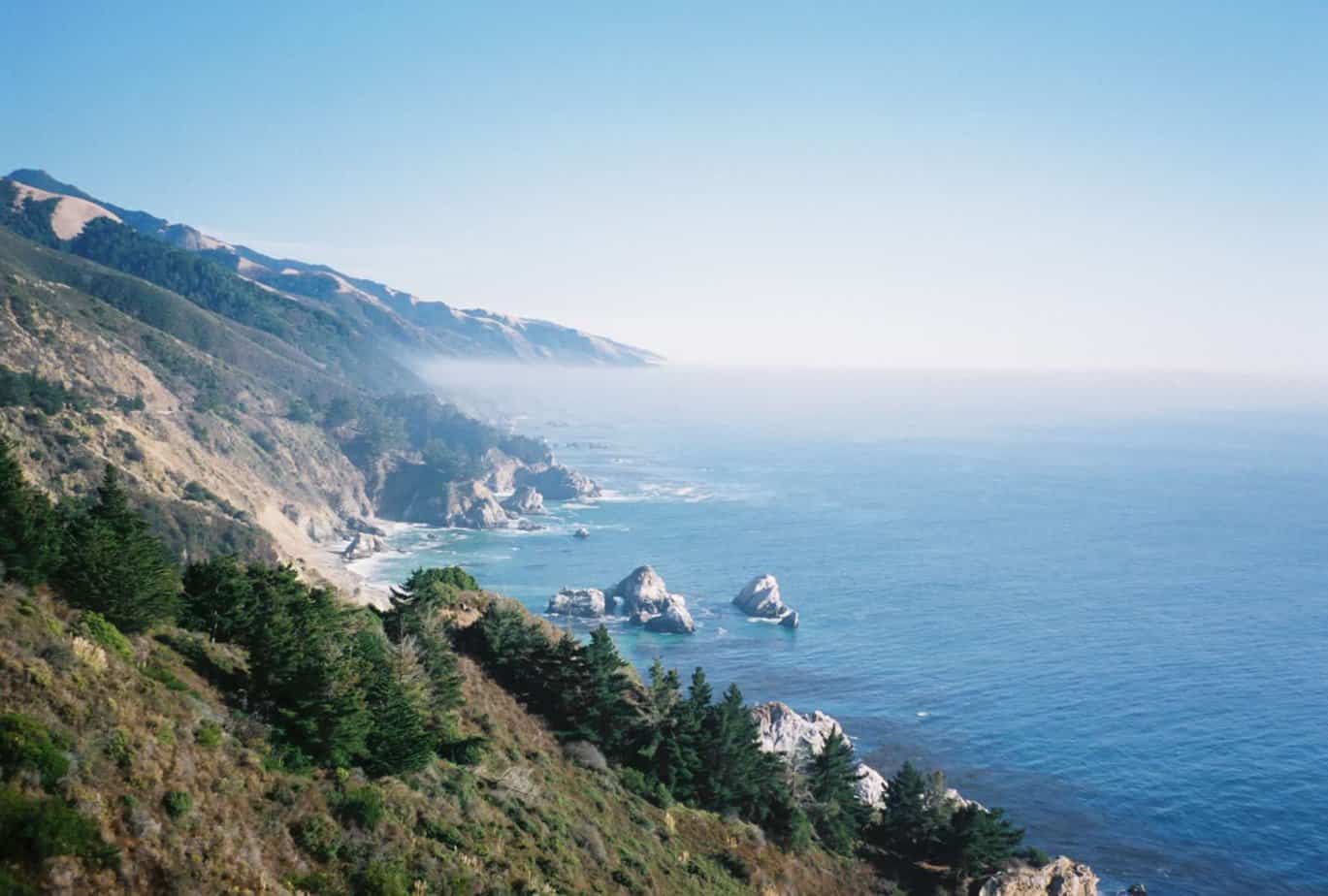 Fog drifts over the pristine shores and coves of Big Sur, California.