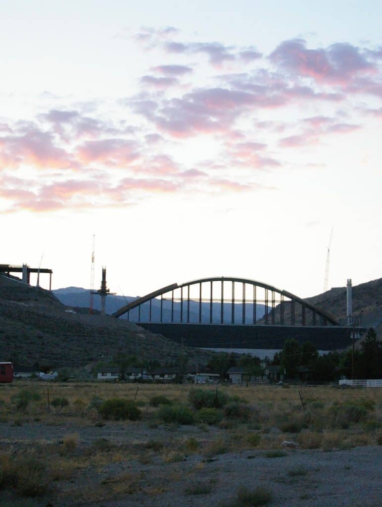 A silhouette of an enormous arch framework stands at the Galena Creek Bride constuction site.