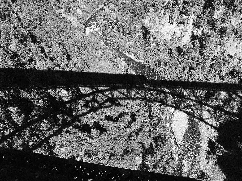 The shadow of the Hurricane Gulch Bridge covers the floor of Hurricane Gulch. Hurricane Gulch Bridge is one of the highest bridges in the US.