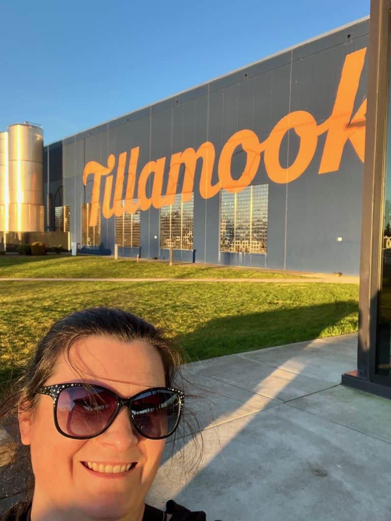 Smiling woman in sunglasses in front of the Tillamook Cheese Factory.