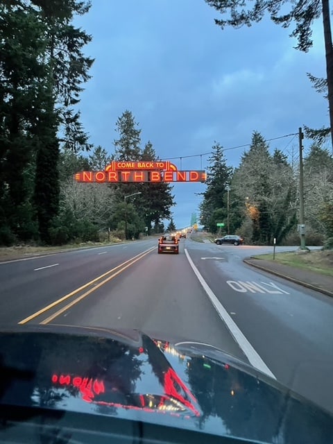 A neon sign hangs on our approach to the Conde McCollough Memorial Bridge. The red neon letters read "Come Back To North Bend."
