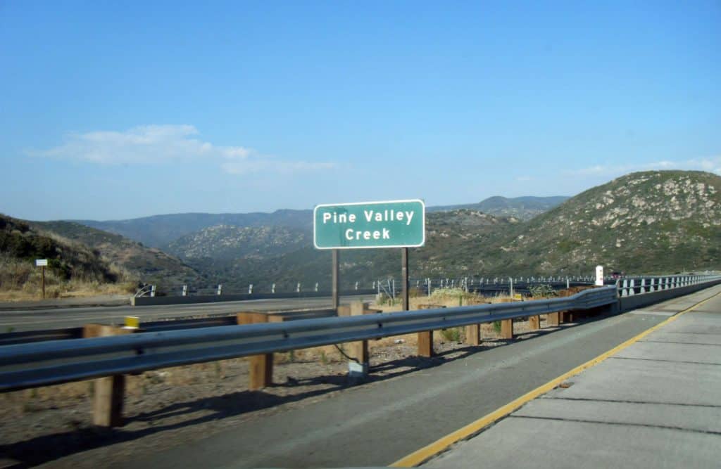 A green freeway sign reads "Pine Valley Creek". The sign stands at the entrance to the Pine Valley Creek Bridge.
