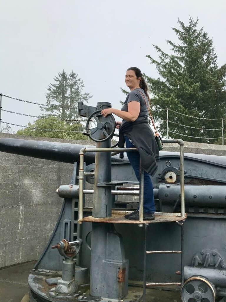 Woman standing on a World War 2 firing gun.