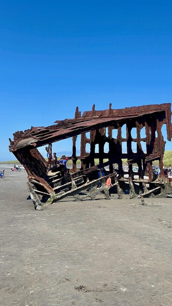 Kids climbing the wreck of the Peter Iredale on a sunny day.