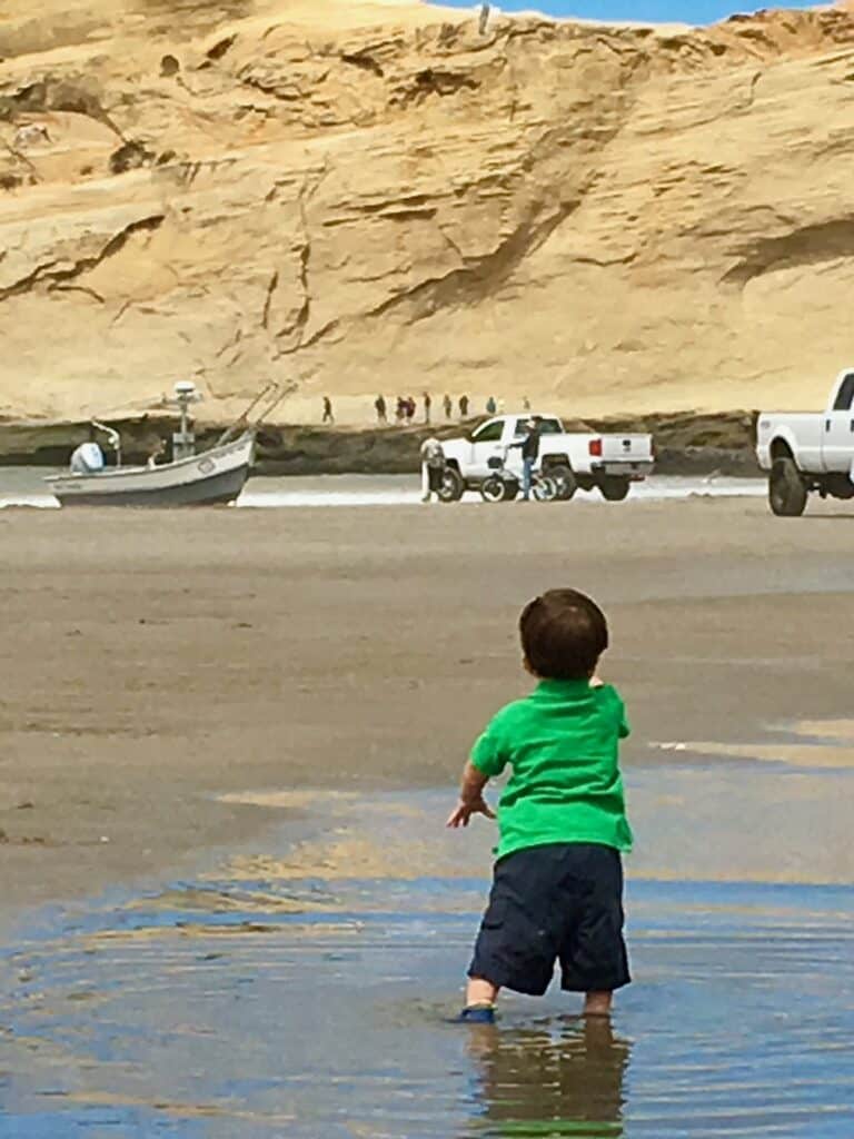 Toddler watching dory boat and truck at Pacific City Beach.