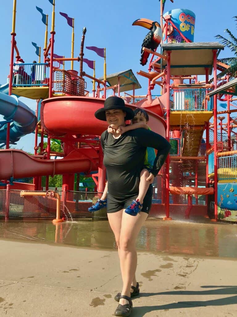 Jenn and our youngest son on piggyback in front of the Paradise Falls water playground at Oceans of Fun.