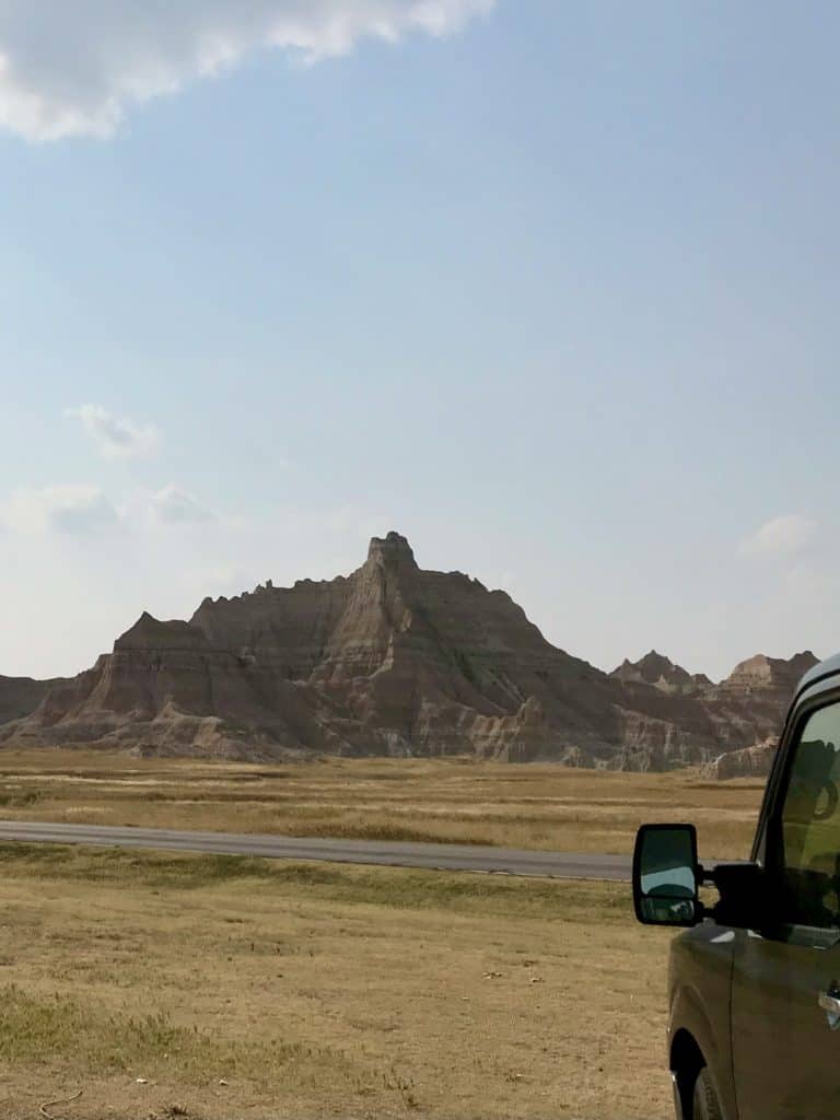 Van pointing towards Badlands rock formation. Driving through Badlands National Park.