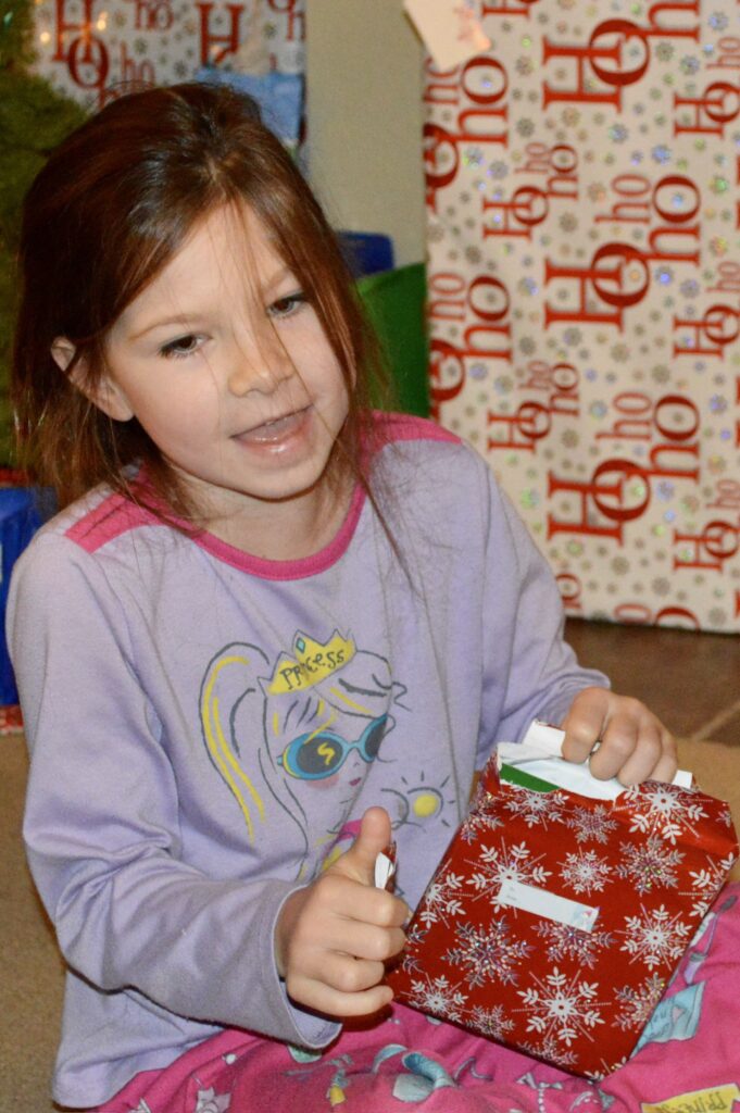 Our daughter opening a gift. Christmas gift planning makes the whole holiday season more pleasant.