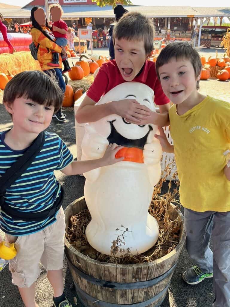 Our boys with a plastic ghost in in front of a pile of pumpkins at a pumpkin patch near Salem Oregon