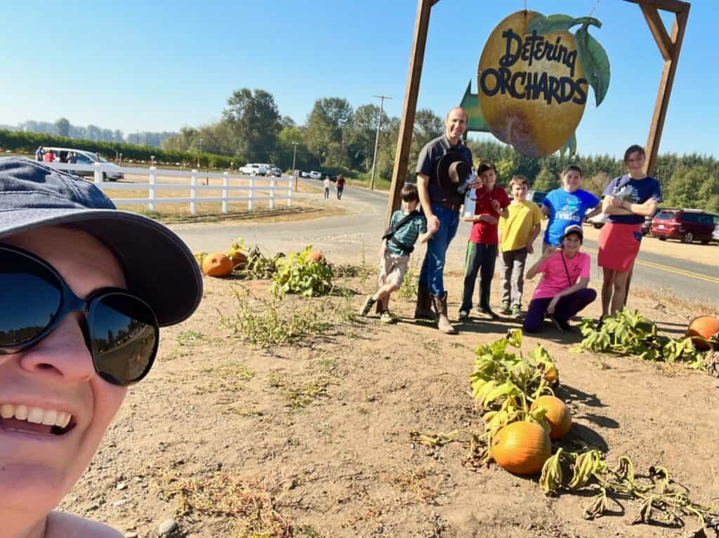 Family photo in front of the Detering Orchards sign. Halloween activities for teens.