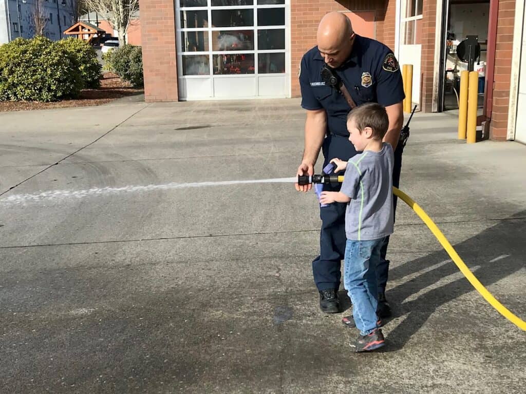 Our son spraying a fire hose with help from a fireman.